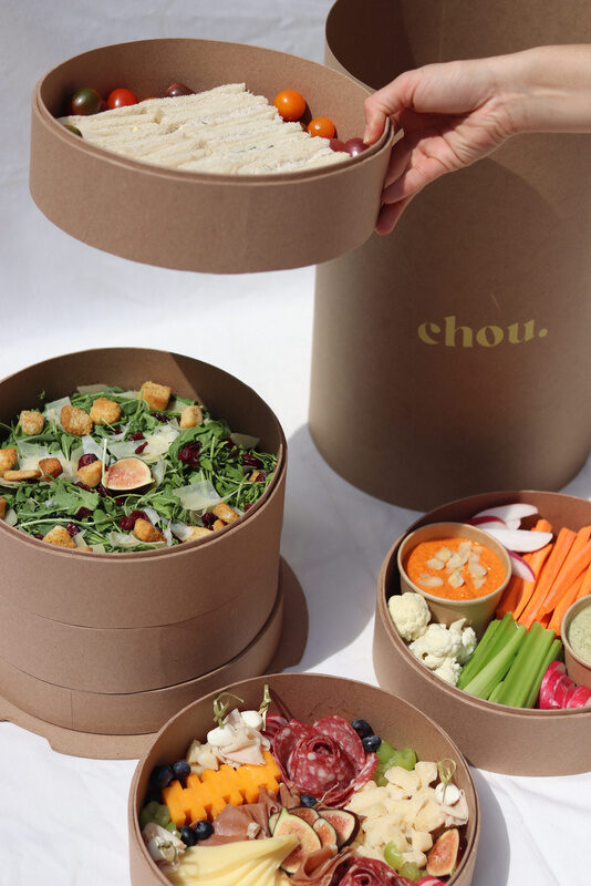 Caja de catering chou.mx abierta con ensaladas y snacks